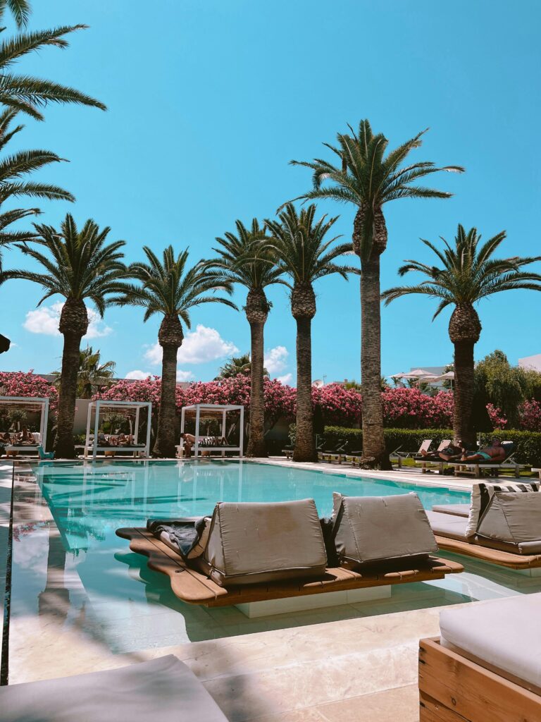 Relaxing poolside with lounge chairs at a luxurious resort under palm trees.